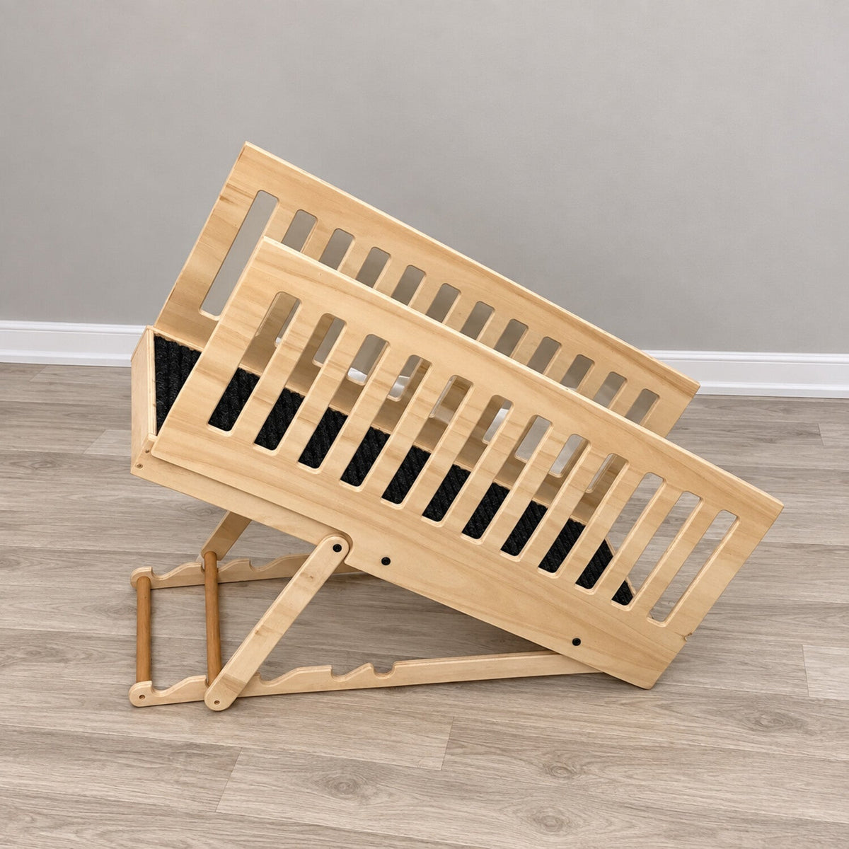 Side view of a natural wood adjustable dog ramp showing the incline support, carpeted walkway and removable rails