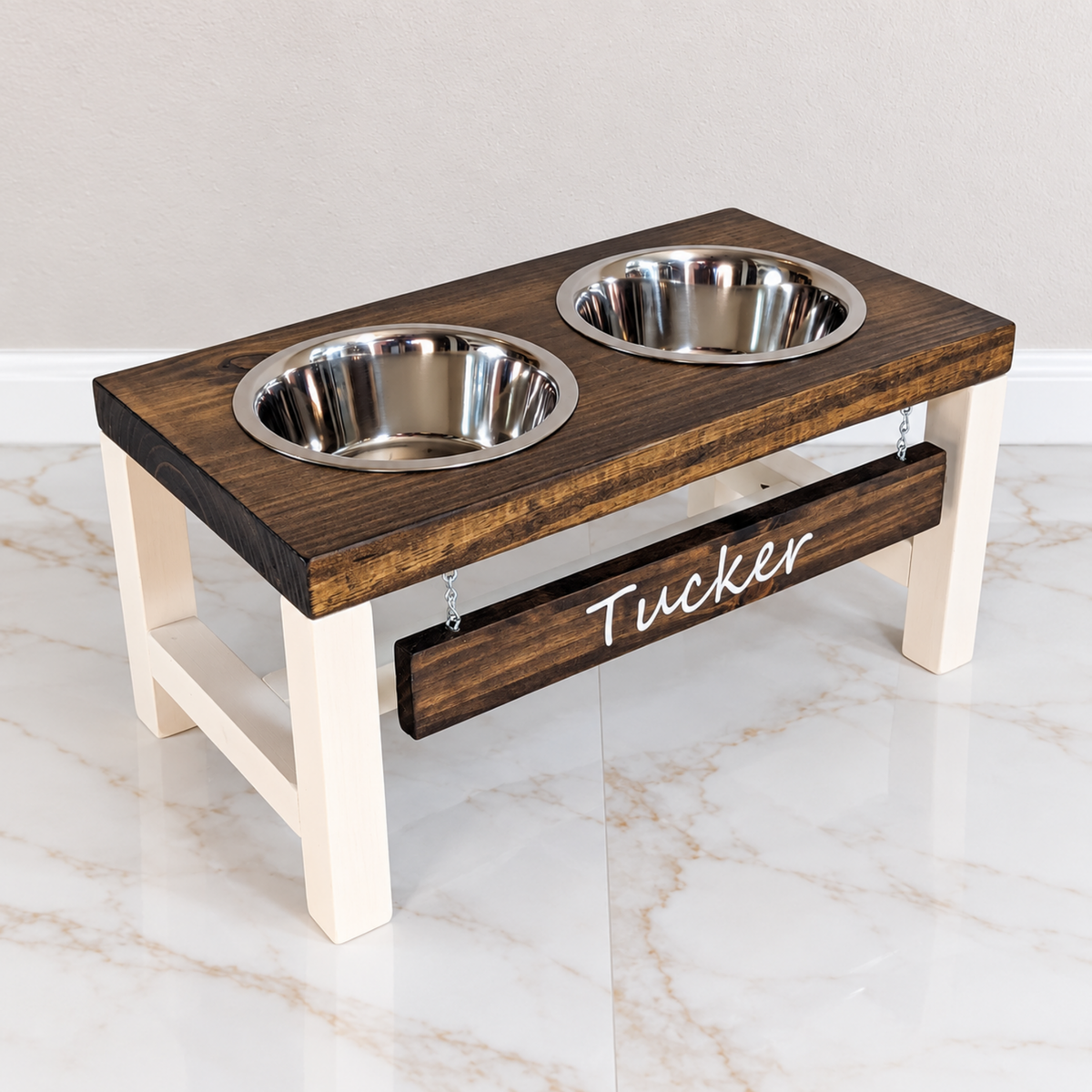 Personalized farmhouse elevated dog bowl stand with dark walnut top, white frame, two stainless bowls and Tucker name board